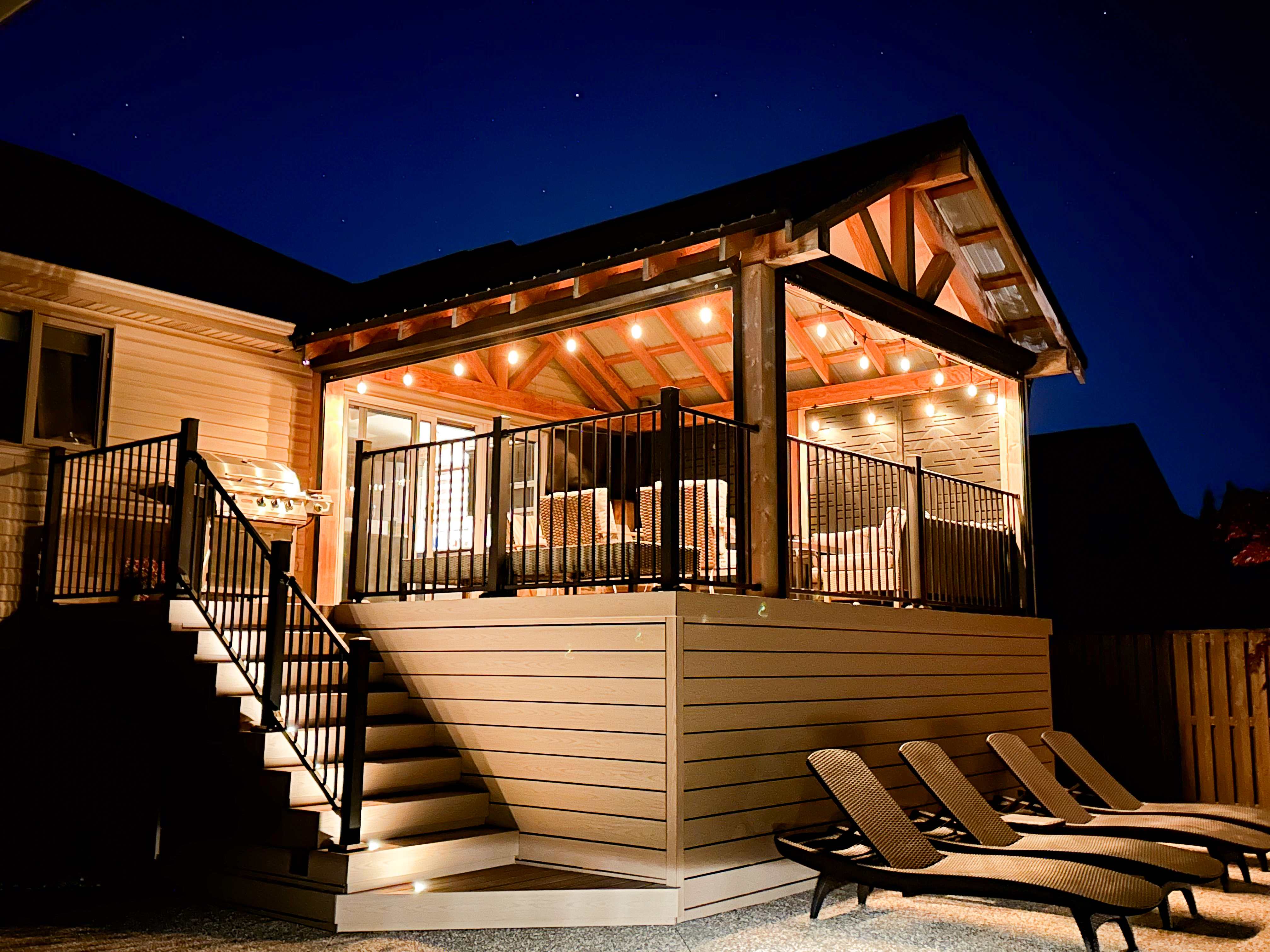 Evening view of elevated deck pavilion with string lights and timber framing